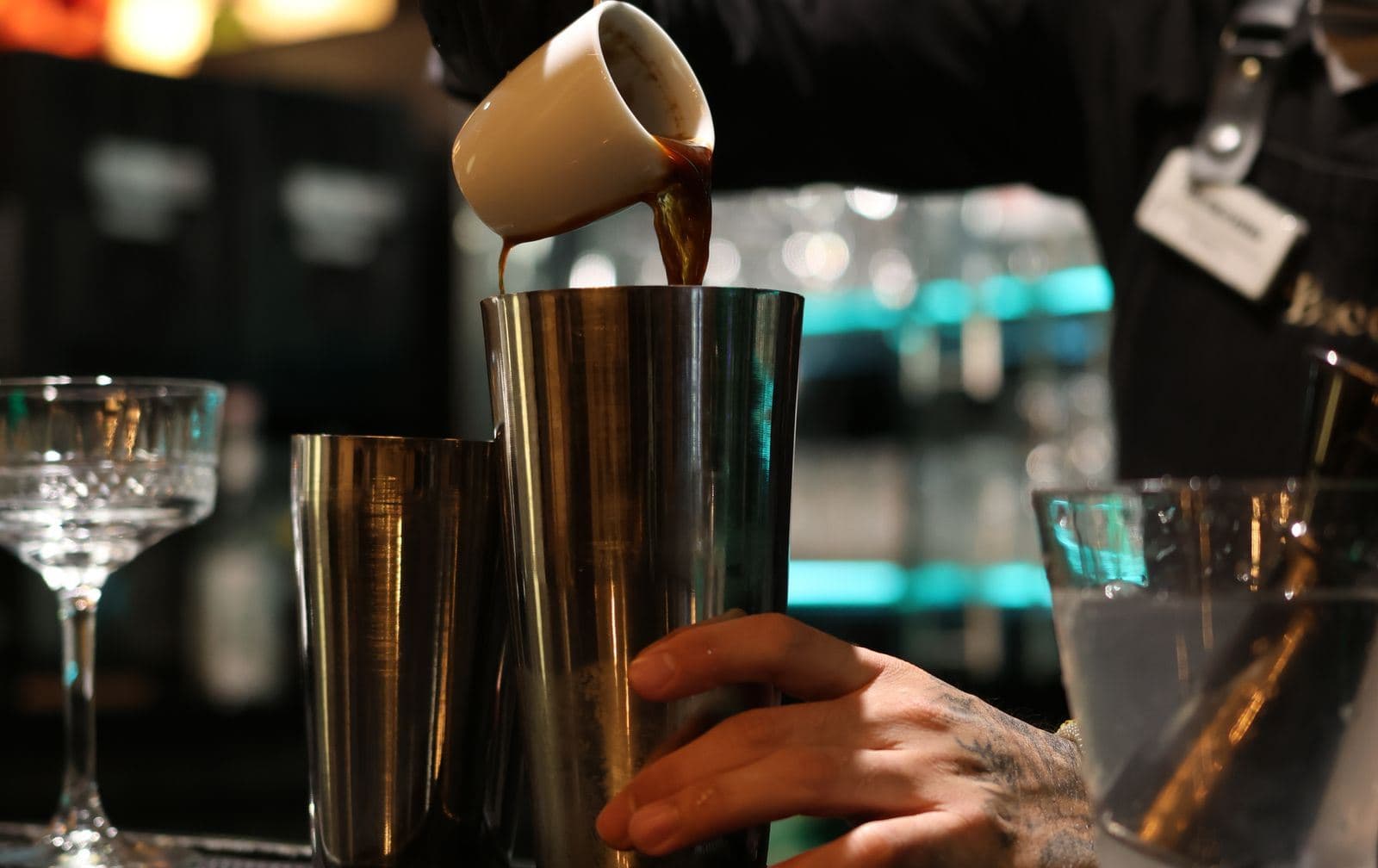 A bartender pouring a drink into a glass.