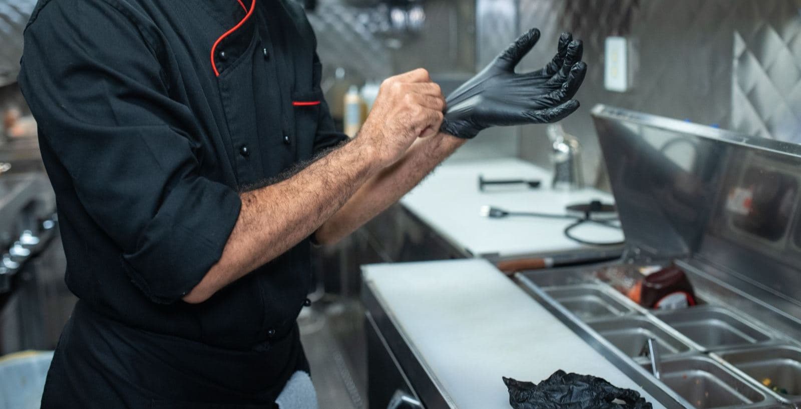 A kitchen worker pulling on a disposable glove.