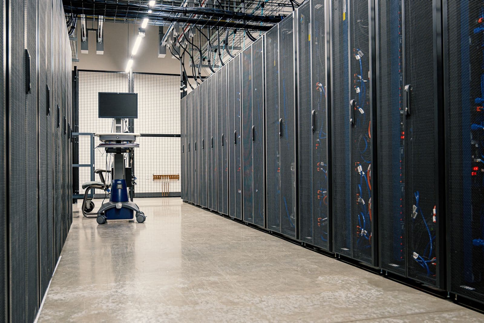 An aisle of server racks and patch cabling in a data center.